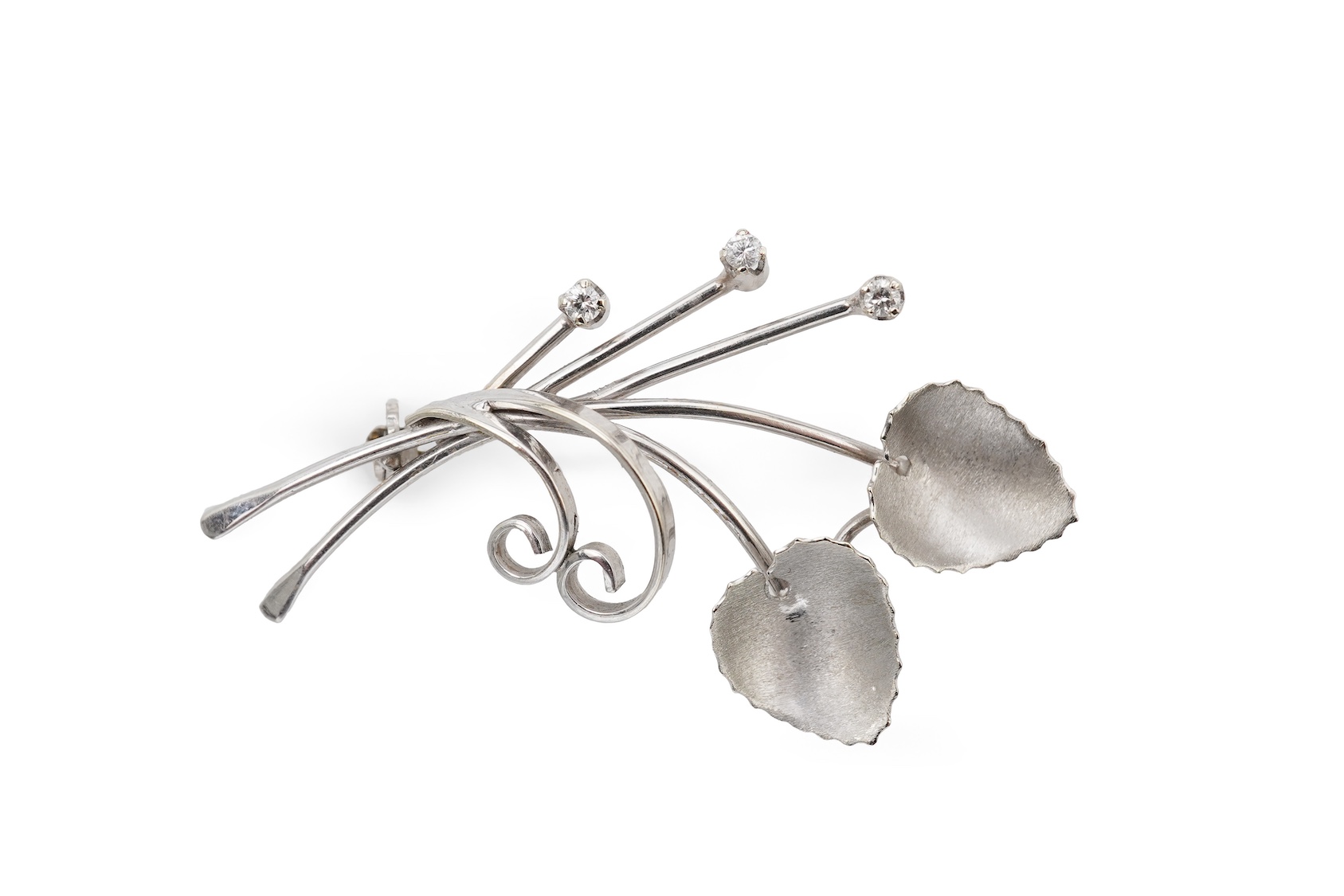 A diamond brooch, designed as stylised foliate spray in white gold, accented with three brilliant-cut diamonds totalling approximately 0.15 carats, length 5.2cm, stamped 750, gross weight 5 grams.